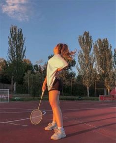 a young woman holding a tennis racquet on top of a tennis ball court