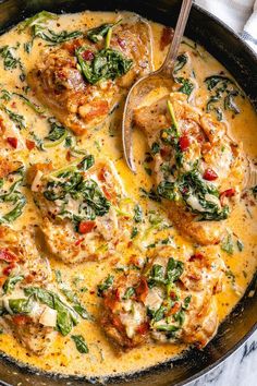 a skillet filled with chicken and spinach covered in gravy on top of a marble counter