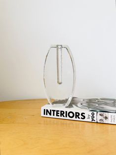 a book sitting on top of a wooden table next to a glass vase filled with water