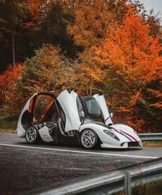 a white sports car with its doors open on the road