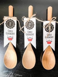 three wooden spoons with labels on them sitting next to each other in front of a black table