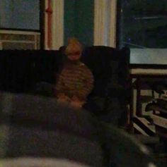 a blurry image of a young boy sitting on a couch in front of a window