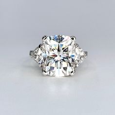 a three stone diamond ring on a white surface with the center surrounded by smaller diamonds