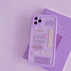 an iphone case with stickers on it sitting on top of a purple book next to a pair of scissors