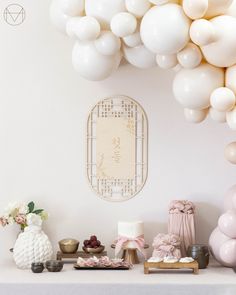 a table topped with lots of white balloons and other decorations on top of a table