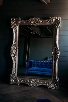 a blue couch sitting in front of a large mirror