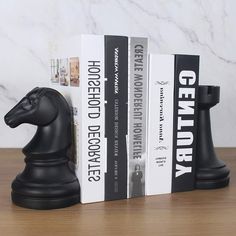 two black chess pieces sitting next to each other on top of a wooden table with books