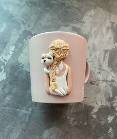 a cup that has some kind of animal on it's side in the shape of a woman