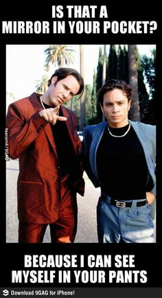 two men standing next to each other in the street pointing at something with their fingers