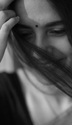 black and white photograph of a woman holding her hair in front of her face with one hand