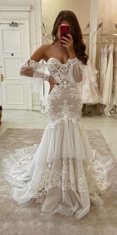 a woman taking a selfie while wearing a wedding dress in front of a mirror