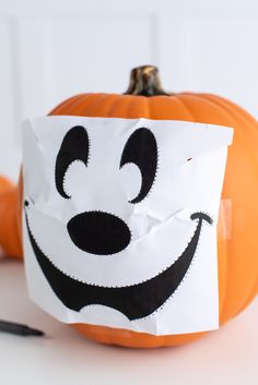 a paper bag with an image of mickey mouse on it next to a small pumpkin