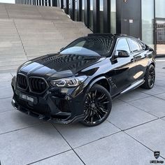 a black bmw suv parked in front of some stairs