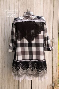 a black and white checkered shirt hanging on a wooden fence with lace trimmings