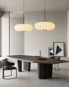 a modern dining table with three lights hanging from it's ceiling and chairs around it