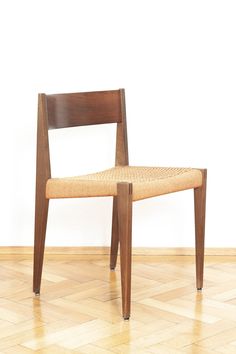 a wooden chair sitting on top of a hard wood floor next to a white wall