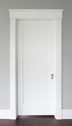 an empty room with a white door and hard wood floor