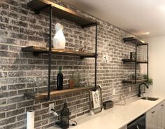 a brick wall with some shelves and bottles on it in a room that has white counter tops