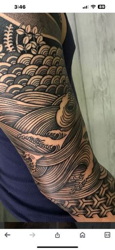 a man's arm covered in black and grey ink with waves coming out of it