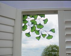 a window with green leaves hanging from it's side and the sky in the background