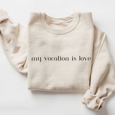 This Catholic crewneck in sand, navy, ash, green, maroon, or dark heather is the perfect cozy sweatshirt for any Christian, Catholic, or person whose mission is to love. This crewneck features a minimal design in a modern quote that reads "my vocation is love".  This quote is from Saint Therese of Lisieux, who was a beautiful example of faith. She helps us live our lives and faith in little ways and small moments. Coupled with the minimal design, this crewneck will serve as an excellent wardrobe staple or gift for a Christian or Catholic mom, dad, teen, or student. Better yet, gift this sweatshirt to a Catholic teen, godchild, or newly Confirmed student.  Ideal for any situation, a unisex heavy blend crewneck sweatshirt is pure comfort. These garments are made from polyester and cotton. Th My Vocation Is Love, Catholic Design, Catholic Clothing, Saint Therese, Modern Quotes, St Therese Of Lisieux, Thérèse Of Lisieux, Design Sweatshirt, Catholic Kids