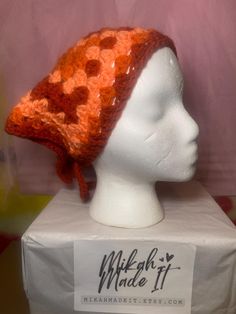 a white mannequin head wearing a red and orange knitted hat with polka dots