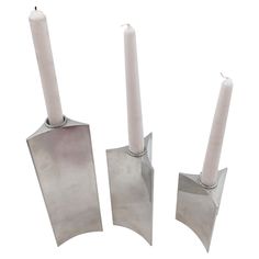 three metal candlesticks sitting next to each other on top of a white surface