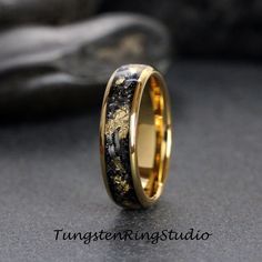 a wedding ring with gold and black inlays on the inside, sitting on a table