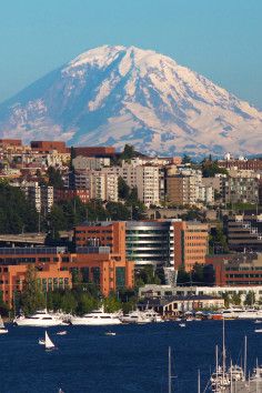 boats are in the water near some buildings and snow capped mountain