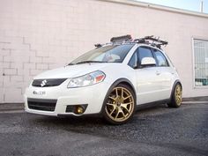 a white car with gold rims parked in front of a building