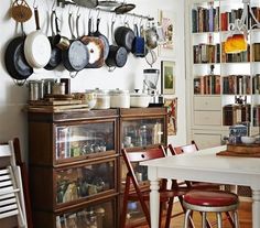 the kitchen has many pots and pans hanging on the wall above the dining room table