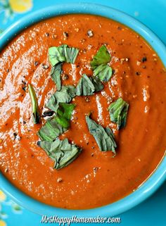 a blue bowl filled with red sauce and green leaves