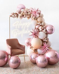 a balloon arch with pink and white balloons on the floor next to an orange chair