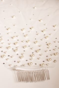 a hair comb with pearls on it sitting on top of a white sheeted surface