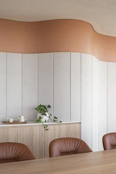 an empty conference room with leather chairs and a wooden table in front of a white paneled wall