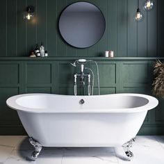 a white bath tub sitting in a bathroom next to a mirror and lights on the wall