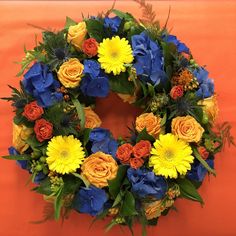 a wreath with yellow and blue flowers on an orange background