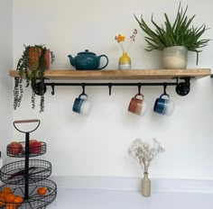 a shelf filled with pots and mugs next to a potted plant