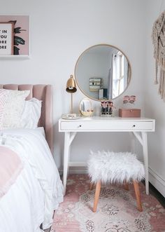 a white desk with a mirror, stool and pink rug in a small bedroom area