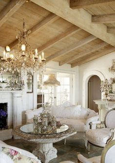 a living room filled with furniture and a chandelier hanging from the ceiling in front of a fire place