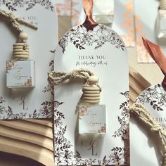 two bottles of perfume sitting next to each other on top of a wooden table with tags