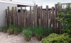 a fence made out of old wooden boards and sticks with grass growing in between them