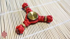 a red rope bracelet with a gold button on it sitting on top of a bamboo mat