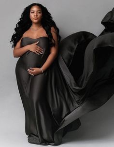 a pregnant woman in a black gown posing for a photo with her hands on her belly