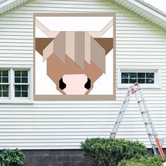 an image of a cow's head on the side of a house with a ladder in front of it