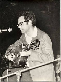 a man playing a guitar in front of a microphone