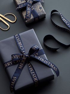 presents wrapped in blue ribbon and tied with gold scissors on top of a table next to each other