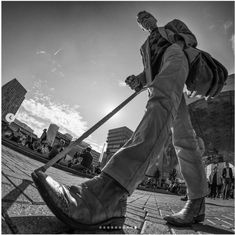 black and white photograph of a man walking on the sidewalk with his cane in hand