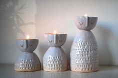 three white ceramic candlesticks sitting on top of a table