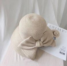 a hat with a bow on it sitting on top of a white bed spreader